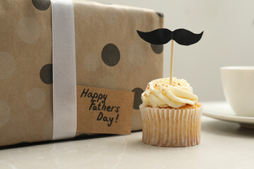 Delicious cupcake with mustache topper, present and card with phrase Happy Father's Day on light...