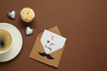 Father's day celebration. Card with phrase I Love You Daddy, cup of aromatic coffee, cupcake and...