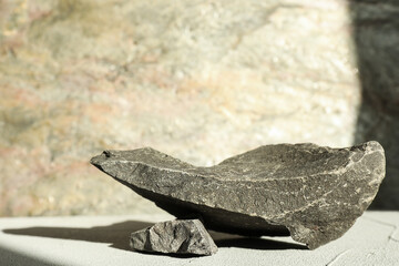 Presentation of product. Podium made of stones on light textured table. Space for text