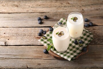 Composition with tasty yogurt in glasses and blueberries on wooden table. Space for text