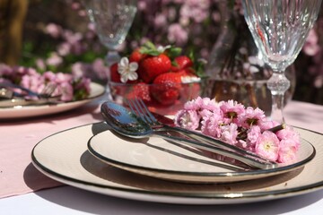 Stylish table setting with beautiful spring flowers in garden, closeup