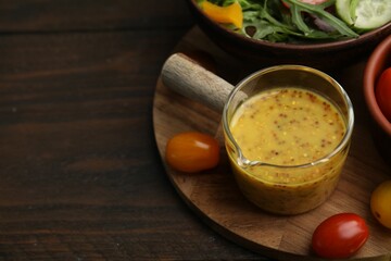 Tasty vinegar based sauce (Vinaigrette), salad and tomatoes on wooden table, closeup. Space for text