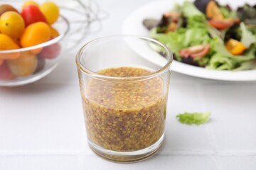 Tasty vinegar based sauce (Vinaigrette) in glass on light tiled table, closeup
