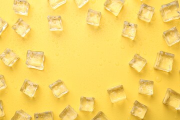 Crystal clear ice cubes on yellow background, flat lay. Space for text