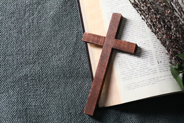 Bible, wooden cross and willow branches on color cloth, flat lay. Space for text