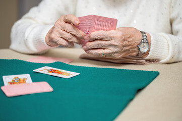 Active retirement, group of elderly women having fun playing cards game at nursing home. High...