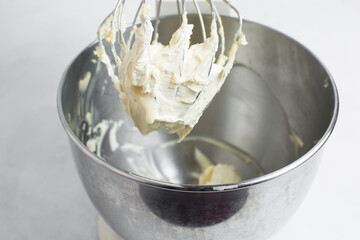 Cream colored american buttercream on a whisk attachment