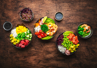 Balanced diet poke bowls with tuna, salmon, shrimp, vegetables, legumes, avocado and rice, wood table background, top view