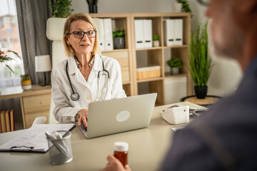 Patient hold medicine while doctor show him medical document