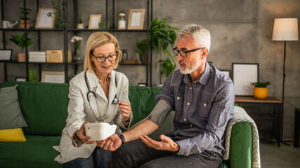 mature man have home visit by a doctor to measure his blood pressure