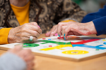 Group of unrecognizable senior woman playing the classic game Ludo or Parchis at nursing home. High quality photo