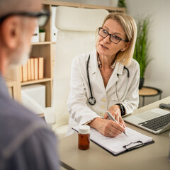 mature woman doctor communicate with mature man patient sit across her