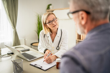 Obraz premium mature woman doctor communicate with mature man patient sit across her