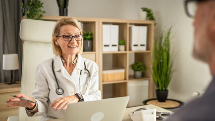 mature woman doctor communicate with mature man patient sit across her
