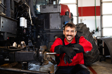 Portrait of experienced mechanic changing wheels on tractor. Service and maintenance of...