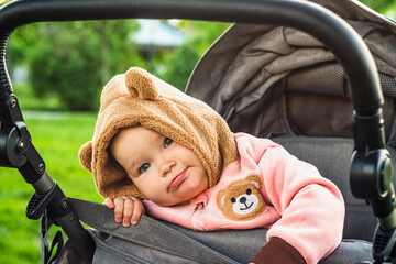 Portrait of a cute toddler girl in a stroller in the park