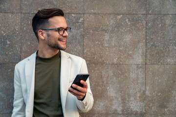 Close up photo of smiling businessman with smart phone. Handsome executive looking away while...