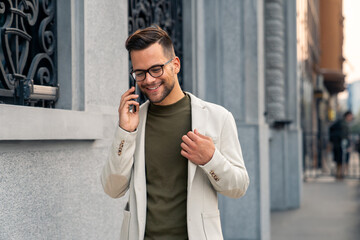 Good looking businessman talking on the phone while walking down the city street. Stylish man with...