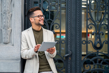 Smiling successful male business person using digital fintech device while standing outside a...