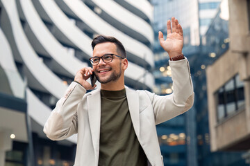 Shot of a young businessman using a smartphone and waving against an urban background.