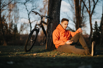A serene setting captures a young man enjoying some downtime in a park with his mountain bike...