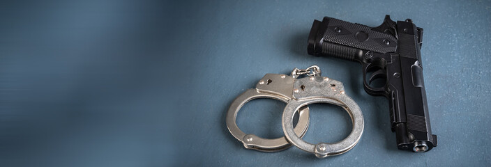 Gun and handcuffs on blue background, stock photo, criminal concept - obrazy, fototapety, plakaty