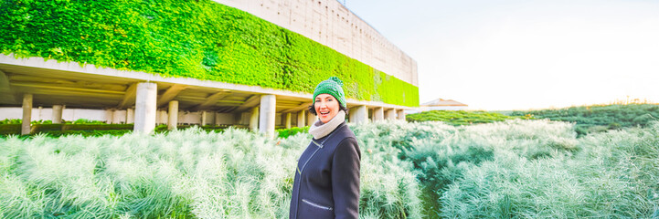 walking woman with modern concrete facade architecture vegetated with plants and green garden