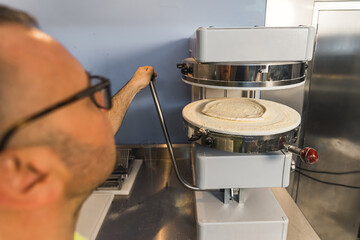 Fototapeta na wymiar preparing dough for pizza win modern machine at the bakery. High quality photo