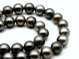 Expensive and luxurious Tahiti black pearls in a stylish necklace on white background, ready to be made into earrings, pendants, bracelets or a choker and sold in jewelry store.