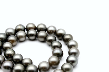 Expensive and luxurious Tahiti black pearls in a stylish necklace on white background, ready to be made into earrings, pendants, bracelets or a choker and sold in jewelry store.