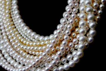 Expensive and luxurious Japanese saltwater Akoya pearls on strands of white, pink and golden organic gems ready to be made into necklaces and sold in jewelry store.
