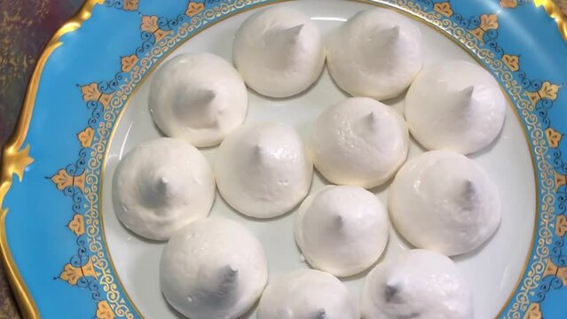 delicious dessert meringue trulli on a golden plate, top view, rotation, zoom in