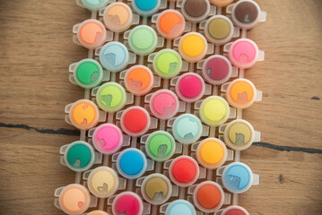 Cute little child painting with paintbrush and colorful paints. Kid hands start painting at the table with art supplies, top view