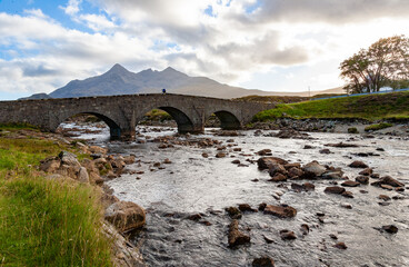 Sligachan Bridge, Isle of Skye, Scotland, with Cuillin Mountains and orange clouds on backround in sunset light, Isle of Skye, Scotland