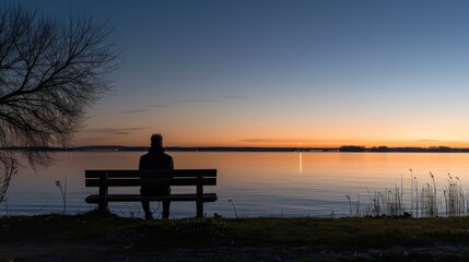 Fototapeta na wymiar Lonely person sitting on a wooden bench alone at dusk looking at the sunset