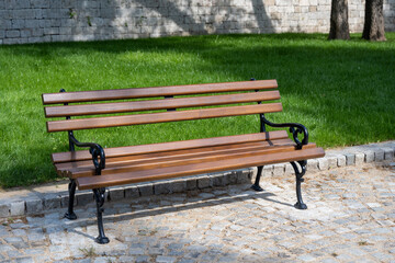 Brown benches for sitting in the city park surrounded by greenery and flowers. Benches for rest and relaxation.