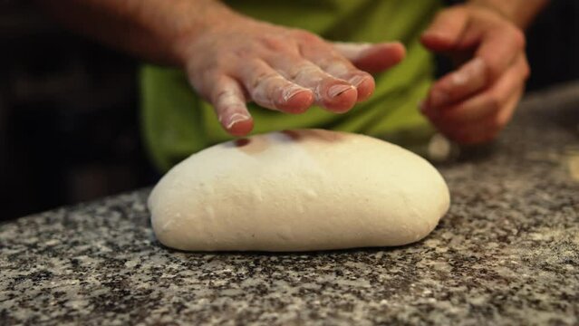 hands steading the dough in the flour, working in the kitchen. High quality 4k footage