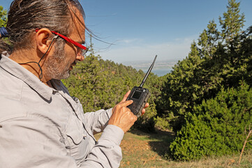 A man checking a photo trap in the forest for wild animals.