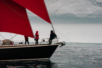photographing photographers on red sailboat cruising past iceberg in Greenland