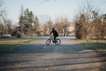 A casual cyclist enjoys a relaxing ride through a verdant park, exemplifying a lifestyle of freedom and health.