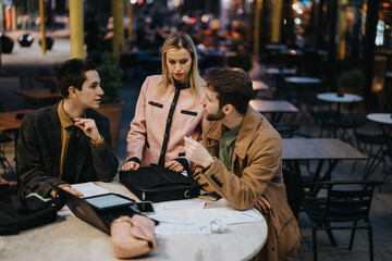 Focused businesspeople discuss project strategies and solutions in an informal outdoor meeting setup, aiming for company success.