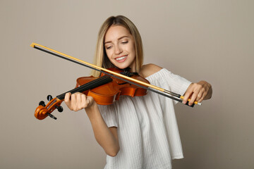 Beautiful woman playing violin on beige background