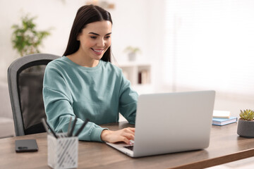 Young woman watching webinar at table in room