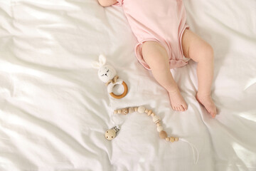 Cute baby with rattle and teether toys on sheets, top view. Space for text