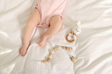 Cute baby with rattle and teether toys on sheets, top view