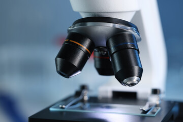 Microscope with glass slide on blurred background, closeup