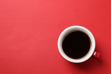 Aromatic coffee in cup on red background, top view. Space for text