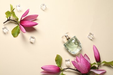 Beautiful pink magnolia flowers, bottle of perfume and ice cubes on beige background, flat lay