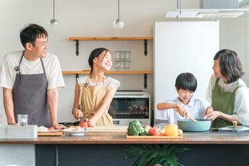 家のキッチンで子供と一緒に料理・クッキング・お手伝いする子供と夫婦・親子・家族
