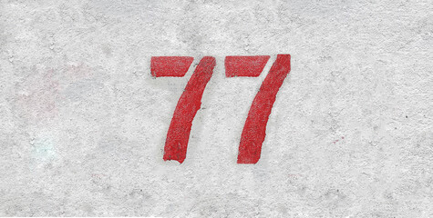 Red Number 77 on the white wall. Spray paint.